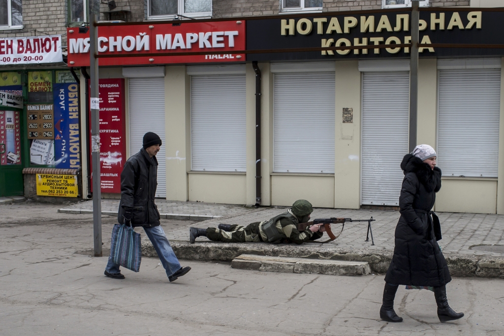 A pro Russian rebel aims his weapon as people pass by during what the rebels said was an anti-terrorist drill in Donetsk