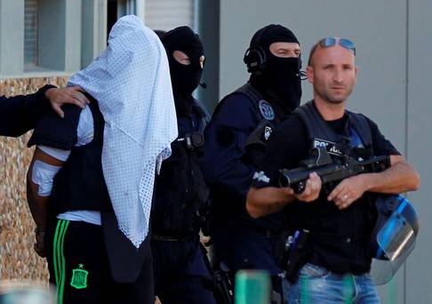 REFILE ADDING DISCLAIMER  A man supposed to be the suspect who held over an attack against a gas company site is escorted by police officers during investigations in Saint-Priest near Lyon France