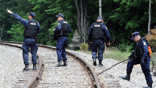 New York State Department of Corrections officers search the railroad tracks after a possible sighting of the two murder convicts who escaped from a northern New York prison two weeks ago Sunday