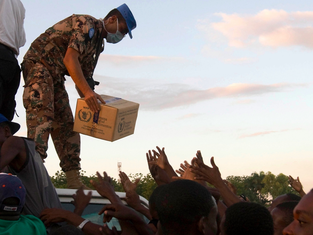 A UN peacekeeper distributes food to internally displaced Haitians in Port-au Prince