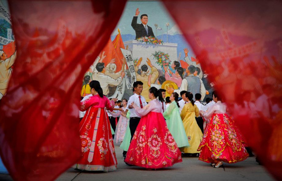 Students participate in a mass dance in front of a mural of the late North Korean leader Kim Il Sung delivering a speech Monday