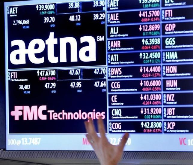 A trader points up at a display on the floor of the New York Stock Exchange