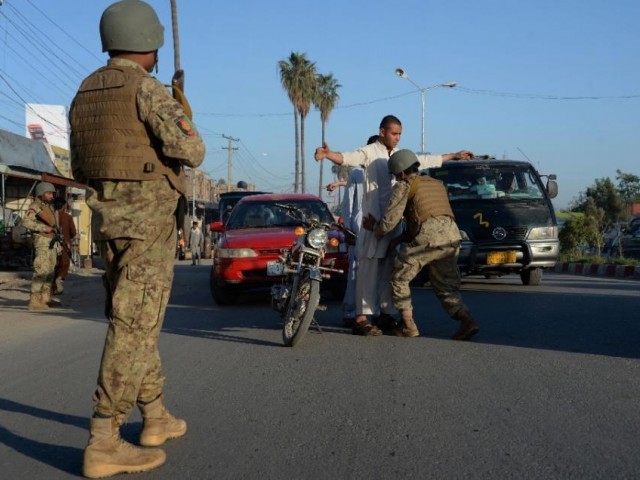 An Afghan soldier searches commuters as others look on at a checkpoint in Jalalabad in Nangarhar province