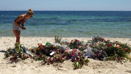 Tourists look at flowers that have been laid on the beach near the RIU Imperial Marhaba hotel in Sousse Tunisia