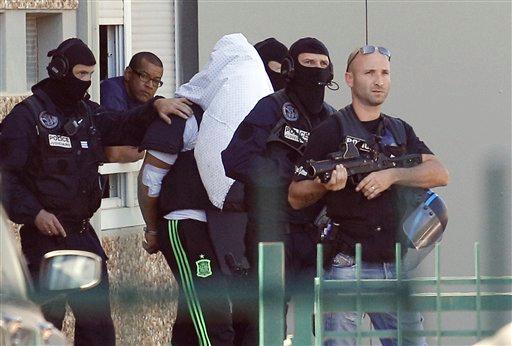 The suspect in the beheading of a businessman Yassine Salhi a towel over his head to mask his face is escorted by police officers as they leave his home in Saint-Priest outside the city of Lyon central France Sunday