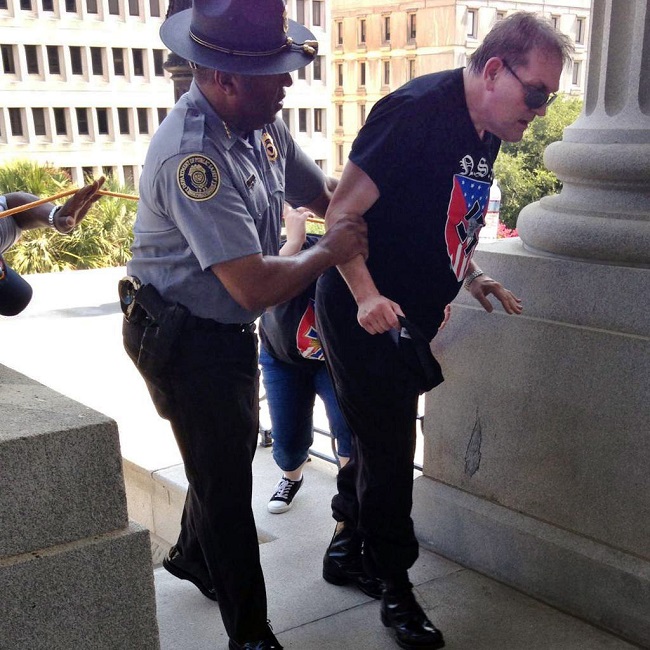 Godfrey police officer Leroy Smith left helps a man wearing National Socialist Movement attire up the stairs during a rally in Columbia S.C. Smith the director of South Carolinas public safety agen