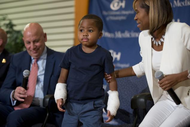 Eight-year-old Zion Harvey is seen showing off his two new hands beside his mother and Dr. L. Scott Levin after undergoing the world's first double-hand transplant on a child