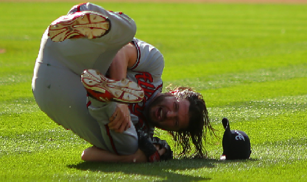 DENVER CO- JULY 11 Jason Grilli #39 of the Atlanta Braves falls to the ground in pain after injuring his ankle running to cover first base on an infield single by Drew Stubbs #13 of the Colorado Rockies during the ninth inning at Coors Field on July 11