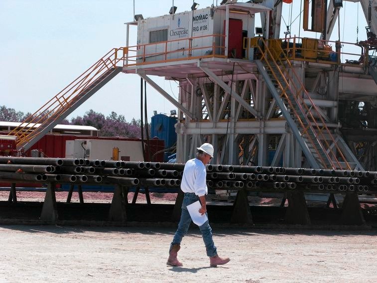 A Chesapeake Energy Corp. worker walks past stacks of drill pipe needed to tap oil and gas trapped deeply in rock like shale at a Chesapeake oil drilling site on the Eagle Ford shale near Crystal City Texas in this