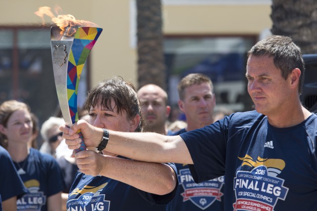 A group of runners including athletes and law enforcement officers carried the Special Olympics torch toward a crowd of about 100 people in Westwood Village on Thursday afternoon