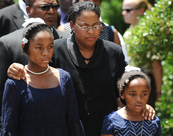 Sen. Clementa Pinckney's wife Jennifer Pinckney center and her daughters Eliana left and Malana right follow his casket into the South Carolina Statehouse Wednesday