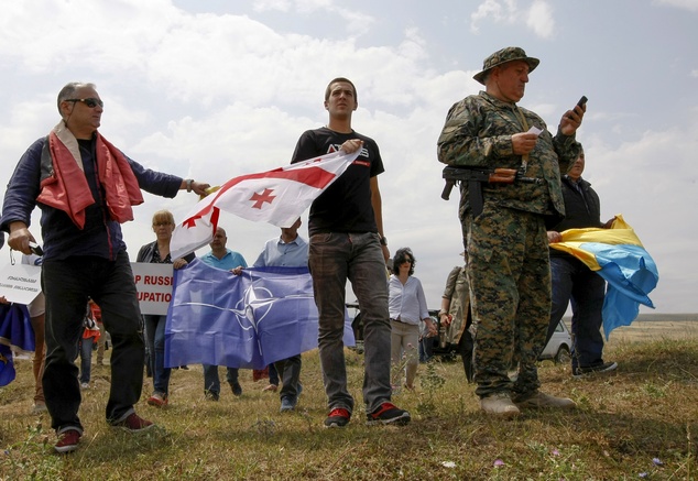 Georgian protesters carry a Georgian flag near Georgia's de-facto border with its breakaway region of South Ossetia in the village of Khurvaleti Georgia Tu