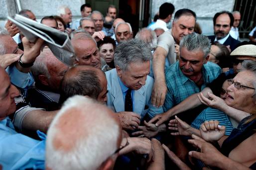 TOPSHOTS
The manager of a national Bank branch delivers priority numbers to pensioners as banks only opened for the retired to allow them to cash up to 120 euros in Athens