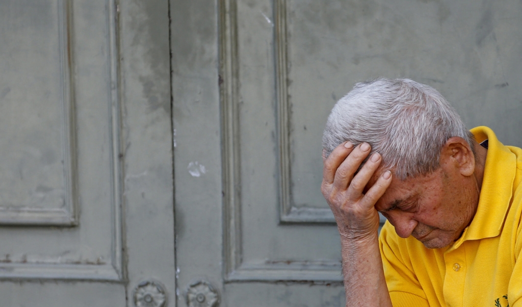 A pensioner waits in front of the main entrance of a National Bank branch to receive part of his pension in central Athens Greece