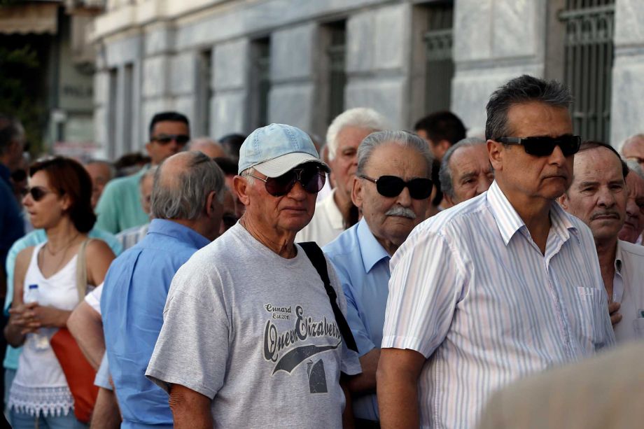 The first customers most of them pensioners stand in a queue to enter a branch at National Bank of Greece headquarters in Athens Monday