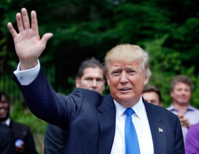 Republican presidential candidate Donald Trump waves as he arrives at a house party in Bedford New Hampshire