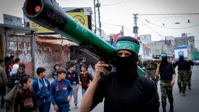 A masked Hamas member carries a model of a rocket during a rally in the Nuseirat refugee camp in the central Gaza Strip