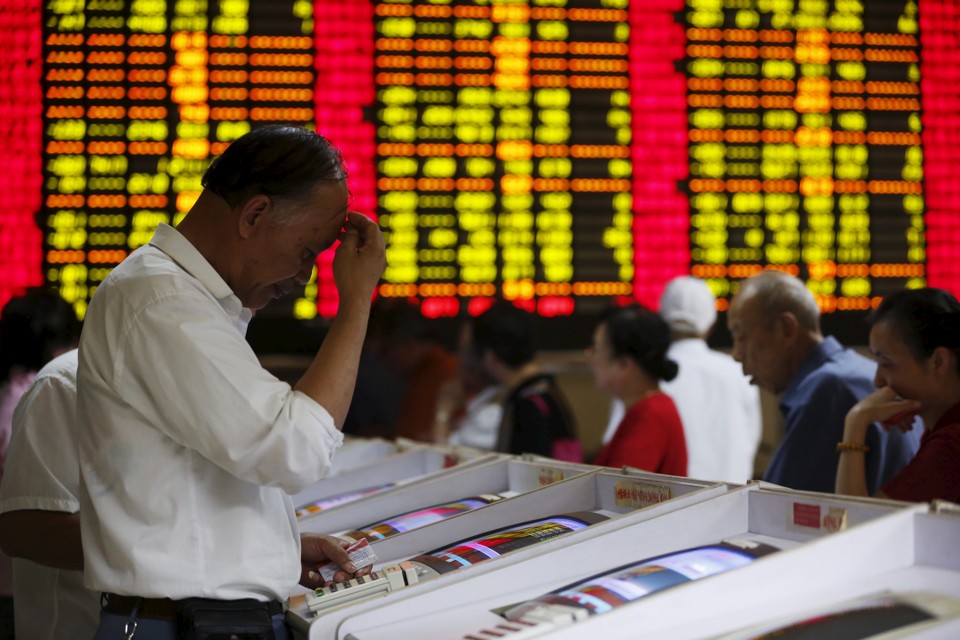 Investors look at computer screens showing stock information at a brokerage house in Shanghai China