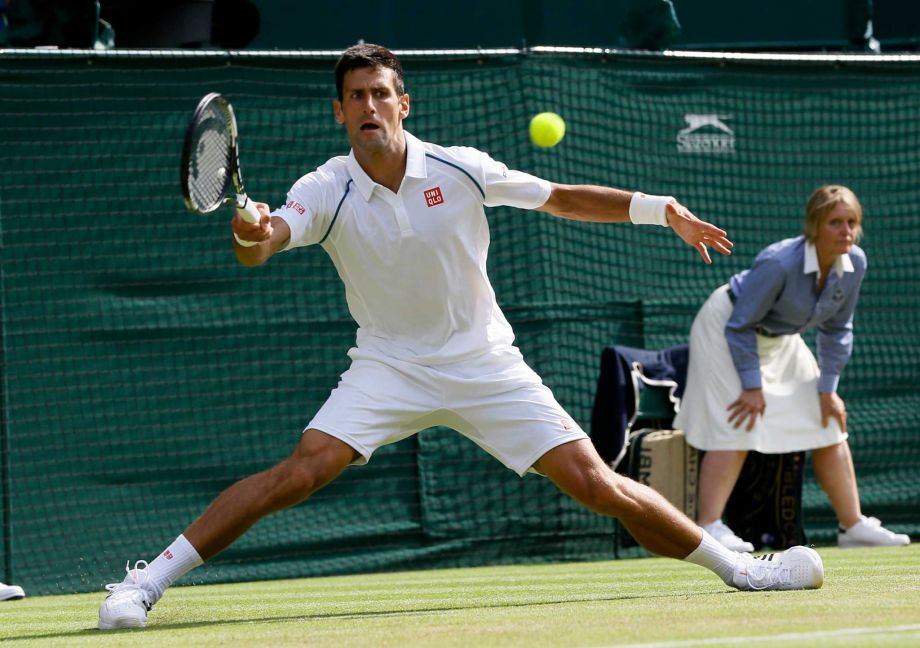 Novak Djokovic of Serbia returns a ball to Bernard Tomic of Australia during their singles match at the All England Lawn Tennis Championships in Wimbledon London Friday