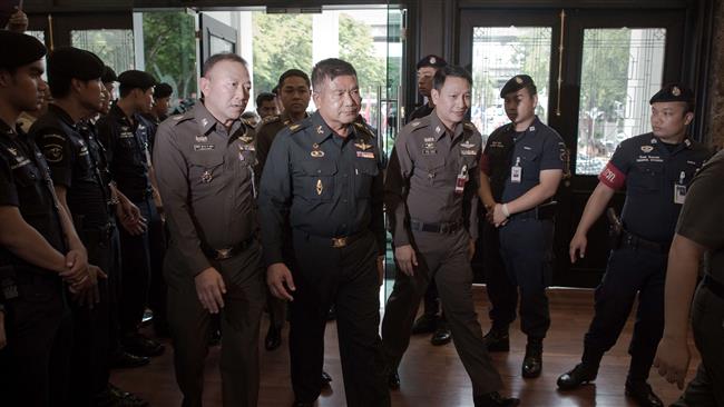 Thai Army Lieutenant General Manas Kongpan is surrounded by police officers at the police headquarters in Bangkok