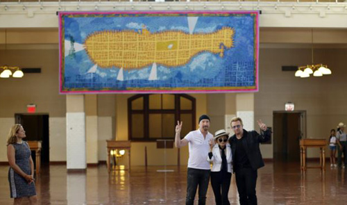 Bono and The Edge of the Irish rock band U2 flank Yoko Ono the widow of John Lennon at the unveiling of a giant tapestry depicting the island of Manhattan as a yellow submarine piloted by a waving Lennon at Ellis Island