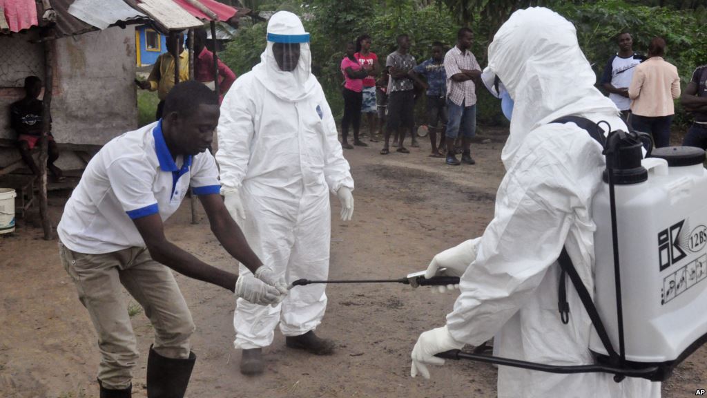 Health workers wash their hands after taking a blood specimen from a child to test for the Ebola virus in an area where a 17-year-old boy died from the virus on the outskirts of Monrovia Liberia