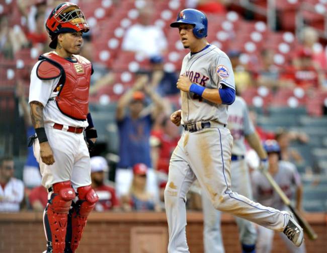 Mets&#39 Wilmer Flores scores past St. Louis Cardinals catcher Yadier Molina on a sacrifice fly by Ruben Tejada during the 18th inning Sunday