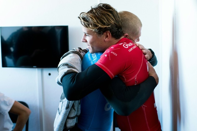 Mick Fanning in blue hugs Julian Wilson who rushed to help as a shark attacked him