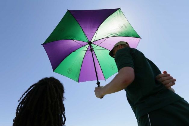 A ball boy shelters Dustin Brown of Germany from the sun during a break in the singles first round match against Yen Hsun Lu of Taiwan at the All England Lawn Tennis Championships in Wimbledon London Tuesday