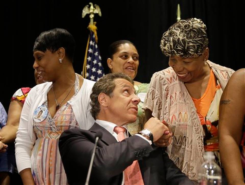 Surrounded by women whose family members were killed by police officers New York Governor Andrew Cuomo center greets Gwen Carr mother of Eric Garner after Cuomo signed an executive order in New York Wednesday