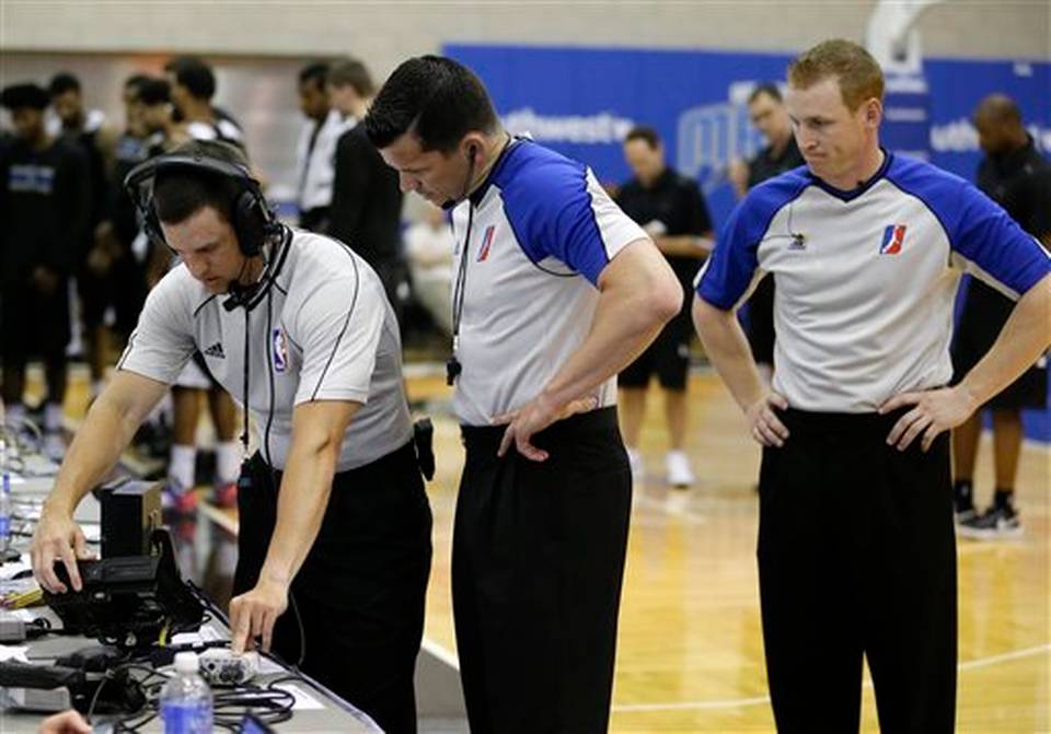 Officials Kevin Scott from left Andy O'Brien and Rusty Phillips look over a replay monitor during the first half of an NBA summer league basketball game between the Orlando Magic Blue and the Memphis Grizzlies, Tuesday