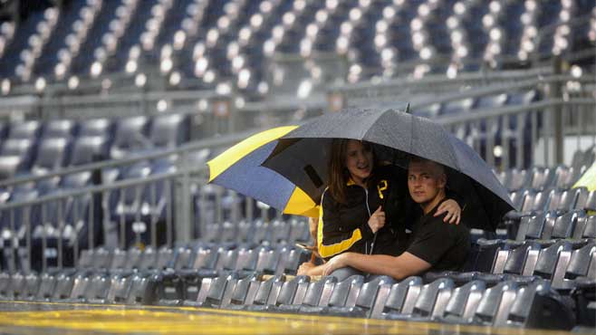 Cathy Mc Connell and Josh Mc Connell stay dry during a rain delay at a baseball game between the Pittsburgh Pirates and the San Diego Padres in Pittsburgh Tuesday