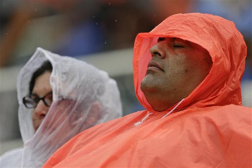 Fans sit in the rain during the third inning of a baseball game between the New York Mets and the Cincinnati Reds Saturday