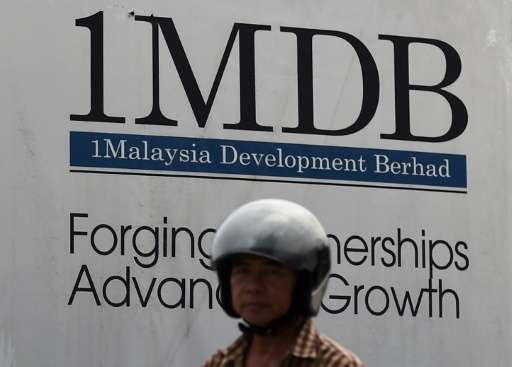 A motor cyclist rides past a hoarding at the construction site of the 1 Malaysia Development Berhad flagship Tun Razak Ex