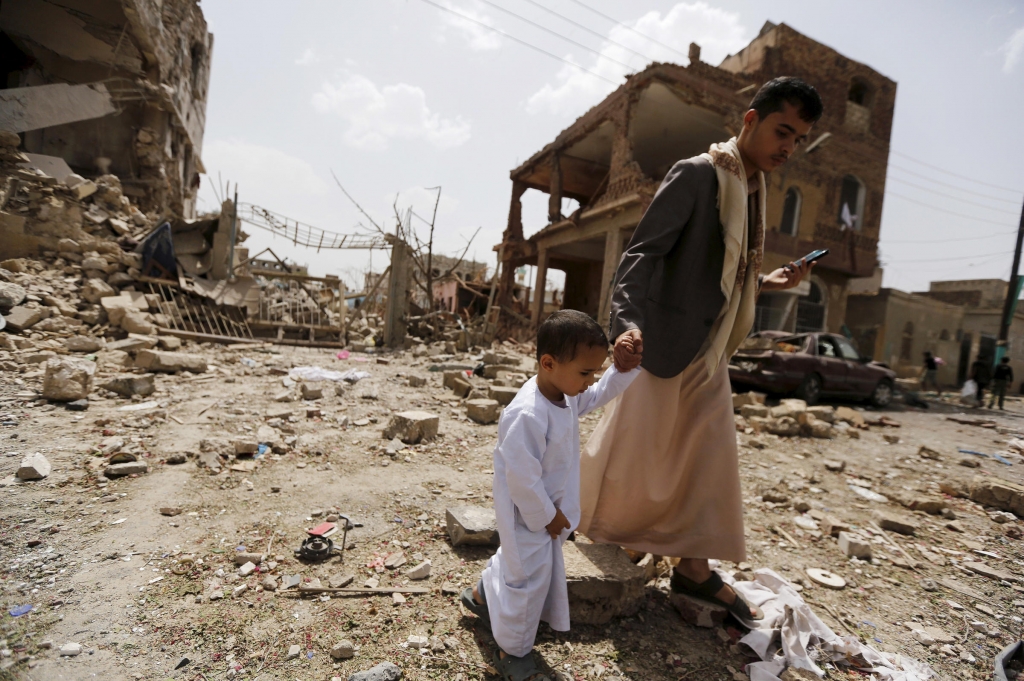 A man and a boy walk at a site hit by a Saudi-led air strike in Yemen's capital Sanaa on July 3. More than a million civilians have been displaced in recent fighting