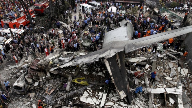 Security forces and rescue teams examine the wreckage of an Indonesian military C-130 Hercules transport plane