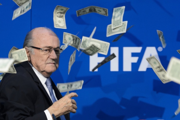 FIFA president Sepp Blatter looks on with fake dollars note flying around him