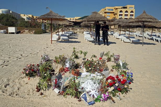 Flowers remain on the beach as police office patrol near the RIU Imperial Marhaba hotel in Sousse Tunisia where 38 people lost their lives after a gunman stormed the beach