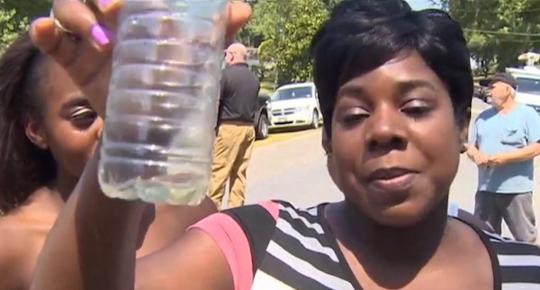 Tammy Miles holds up a bit of water that came from her bathroom tap with worms in