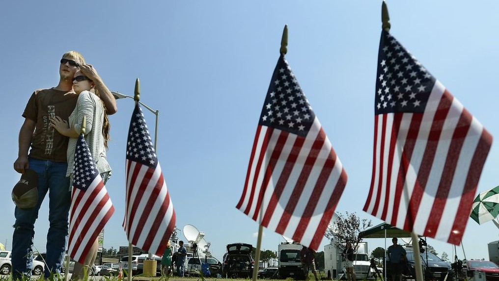 A man and woman comfort one another by a makeshift memorial outside the Armed Forces Career Center Friday