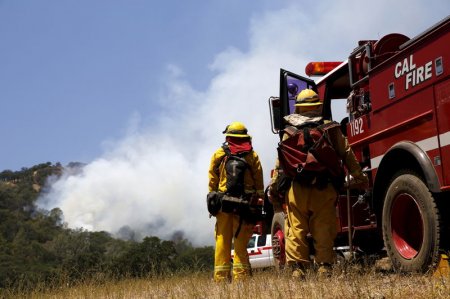 Firefighters look on as smoke from the Wagg Fire rises near Lake Berryessa California