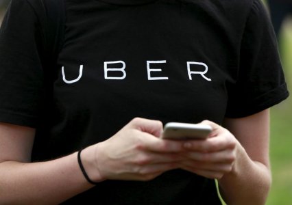 An Uber representative registers people on his smartphone during the kick off of a citywide jobs tour in the Queens borough of New York