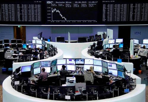 Traders work at their screens in front of the German share price index DAX board at the stock exchange in Frankfurt Germany