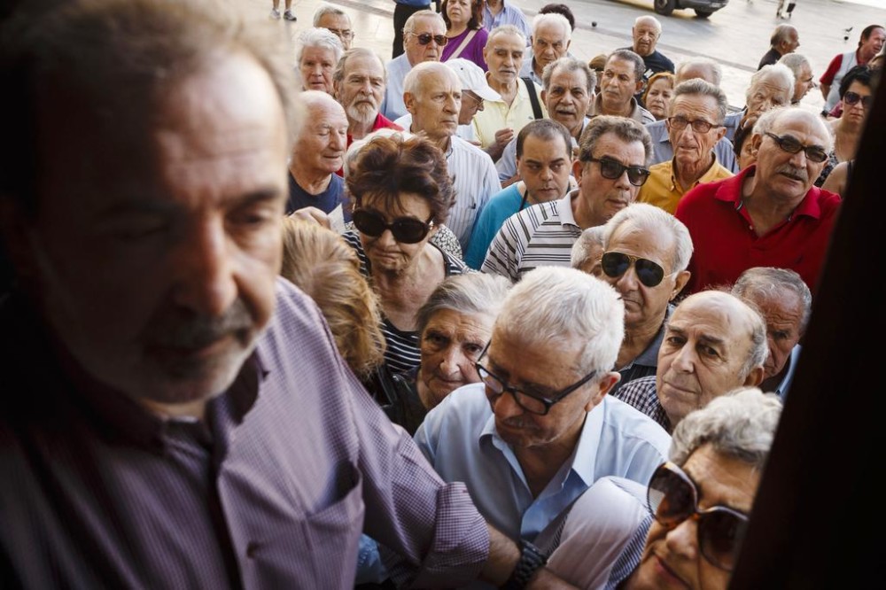 Pensioners wait to be allowed into the National Bank of Greece to withdraw a maximum of 120 euros for the week Thursday