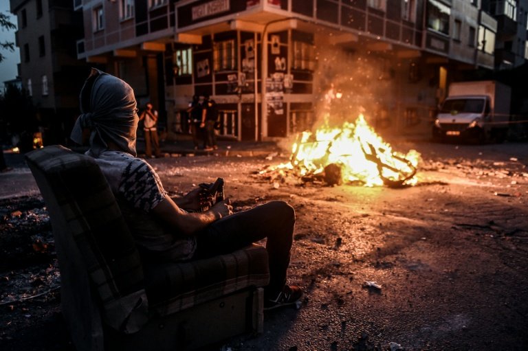 A left-wing protester with his face hidden waits in front of a barricade during clashes with Turkish riot police in Istanbul's Gazi district