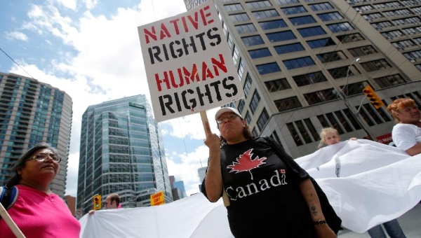 A woman holds a sign as several hundred indigenous people march through the streets of Toronto to bring attention to the plight of indigenous peoples in Canada