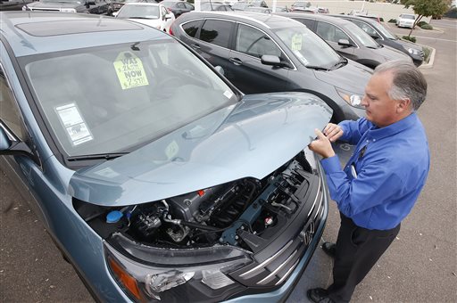 Mike Johnson a sales manager at a Honda car dealership opens the hood of a Honda CRV SUV in Tempe Ariz. Automakers release vehicle sales for June 2015 on Wednesday