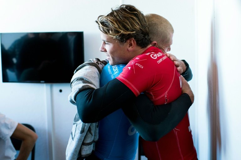 Mick Fanning in blue hugs Julian Wilson who rushed to help as a shark attacked him