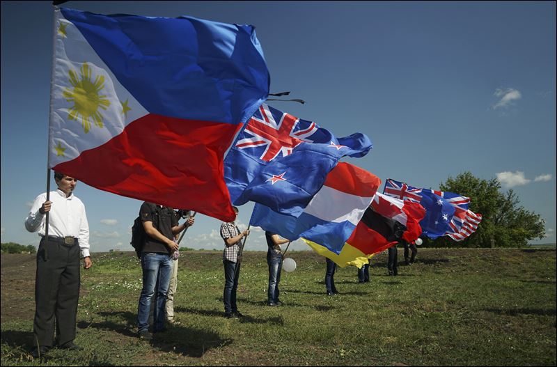 People hold national flags of countries of the passengers who were killed at the crash site of the Malaysia Airlines Flight 17 near the village of Hrabove eastern Ukraine