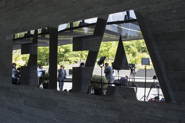 Journalists are reflected in the FIFA logo as they wait in front of the FIFA headquarters in Zurich prior to the press conference of the extraordinary FIFA Executive Committee in Zurich Switzerland Monday